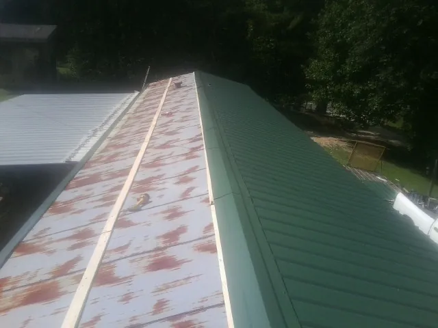 Old rusted panels beside newly installed green metal roofing — Wind Damage Roof Repair by Roofing Brothers in Cowen