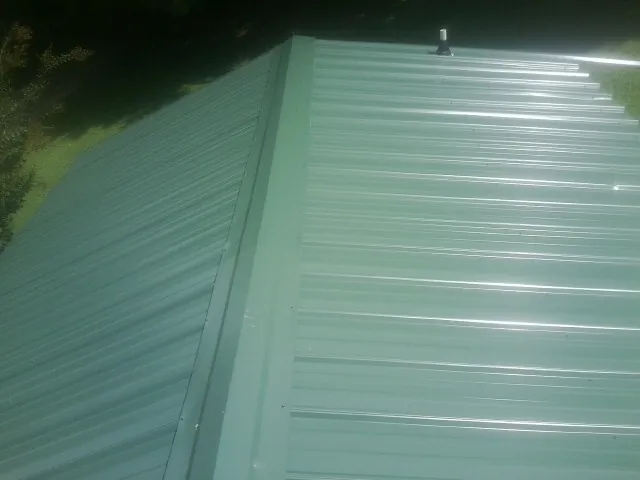 New green metal panels meeting at the ridge of a roof — Flat Roof Repair work by our crew in Cowen