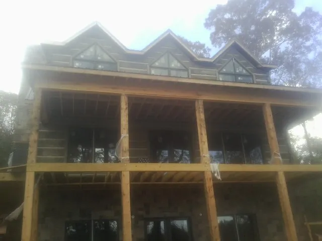 Dormers and porch framing on a large log home under construction — Roof Coating work by our crew in Cowen