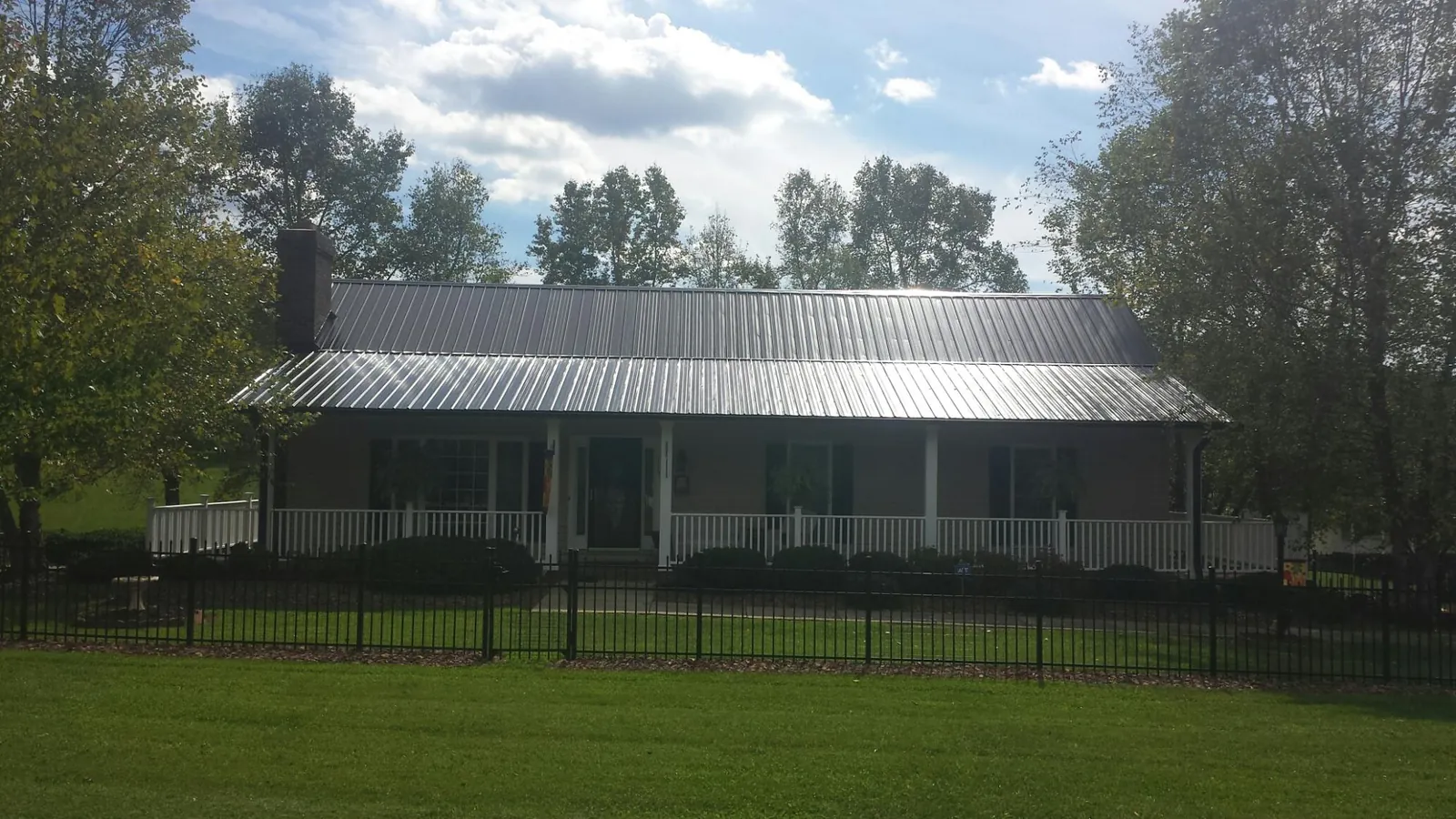 Gray metal roof on a brick ranch with a full width front porch — Gutter Guard Installation work by our crew in Cowen