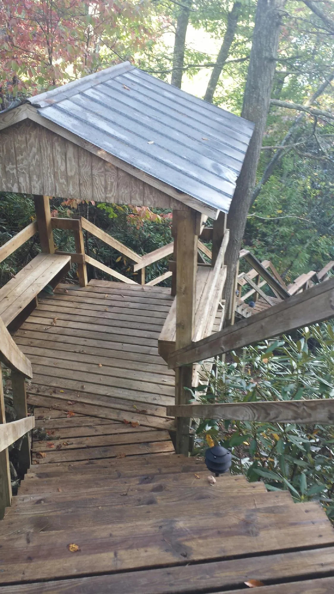 Metal roofed shelter over wooden steps on a wooded walkway — Skylight Repair & Installation work by our crew in Cowen