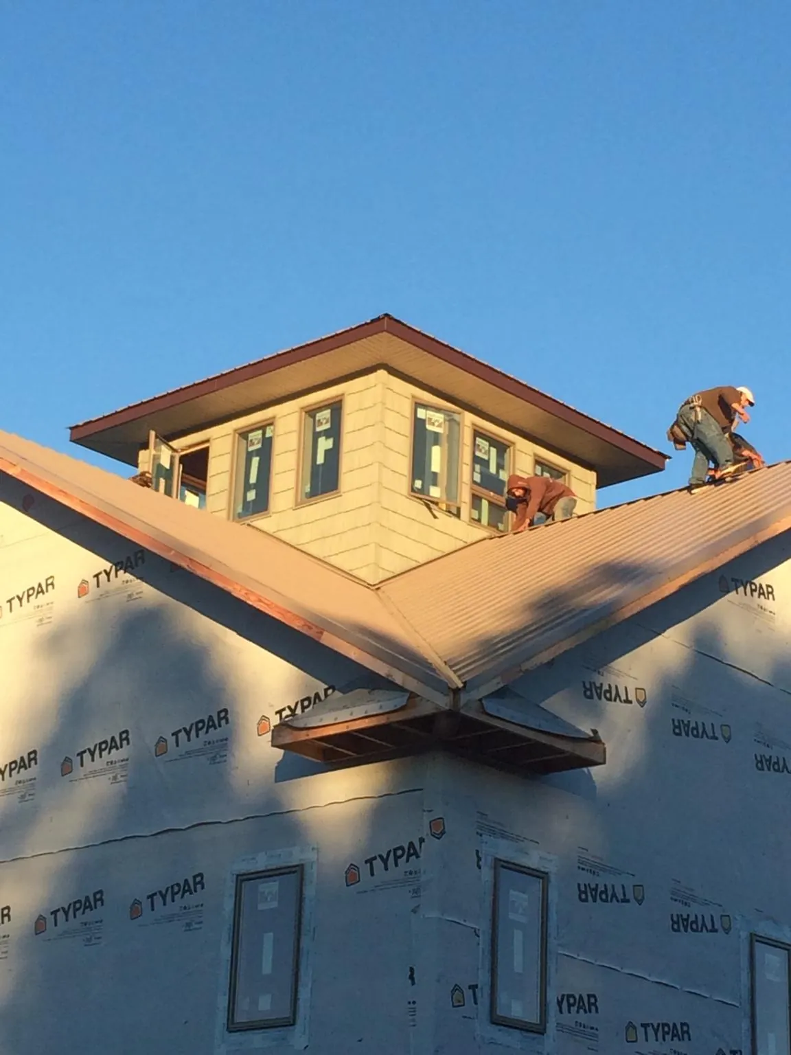 Roofers working around a rooftop cupola on a new metal roof at sunset — Roof Waterproofing in Cowen by Roofing Brothers